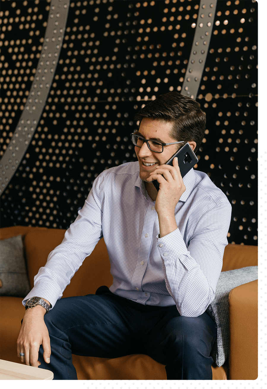 A man smiling while talking on the phone with a client.