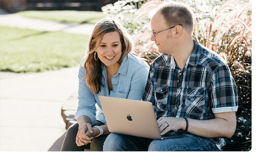 Two employees at Ntara sit together outside looking at a laptop.