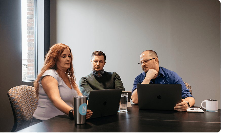 Ntara team members working on laptops in a gray conference room.