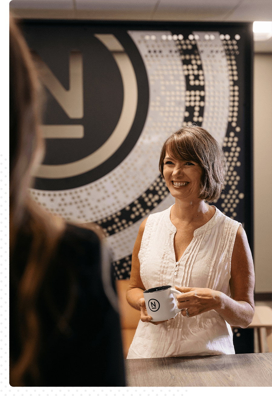 A woman laughing inside of Ntara's cafe, talking with a coworker.