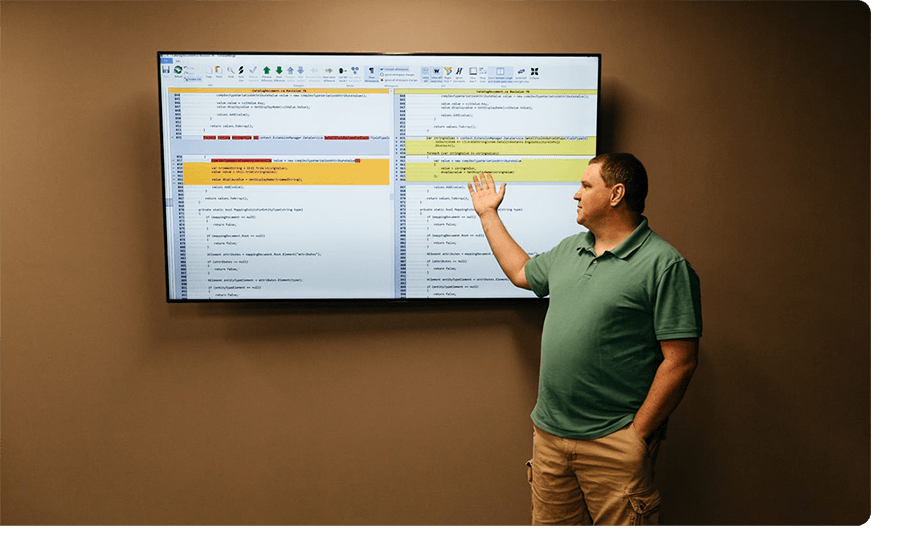 Man in teal polo shirt stands to present something about code development