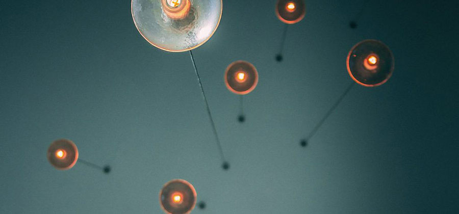 A view from the floor looking up lights hanging from a gray ceiling.
