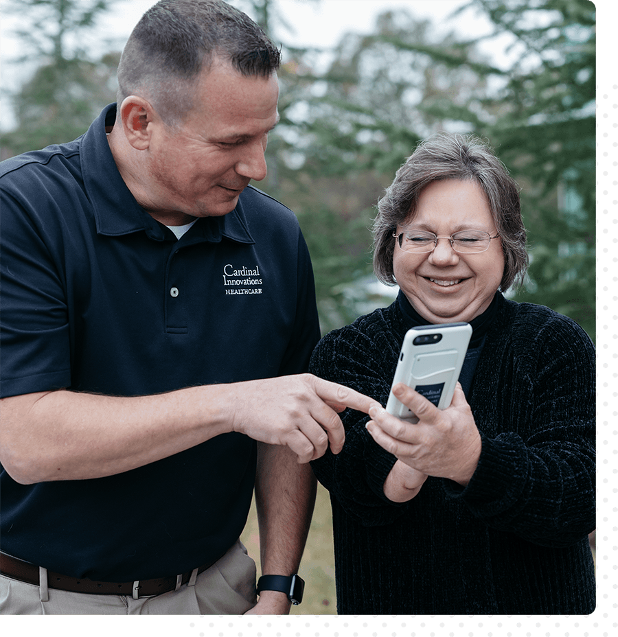 Two people smiling, looking at a mobile phone together.