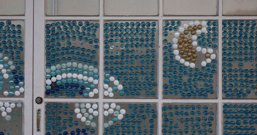 A beautiful mosaic tile wall with blue, white, and yellow glass.