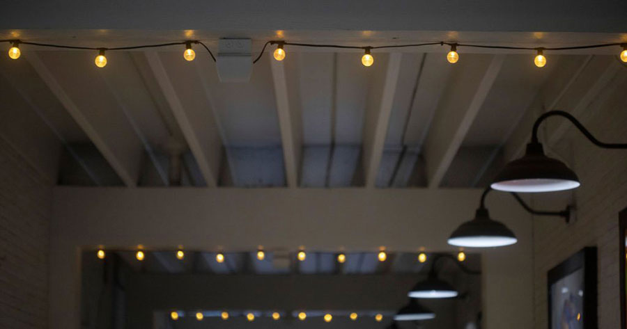 Strings of lights outside under a white wooden patio outside at dusk.