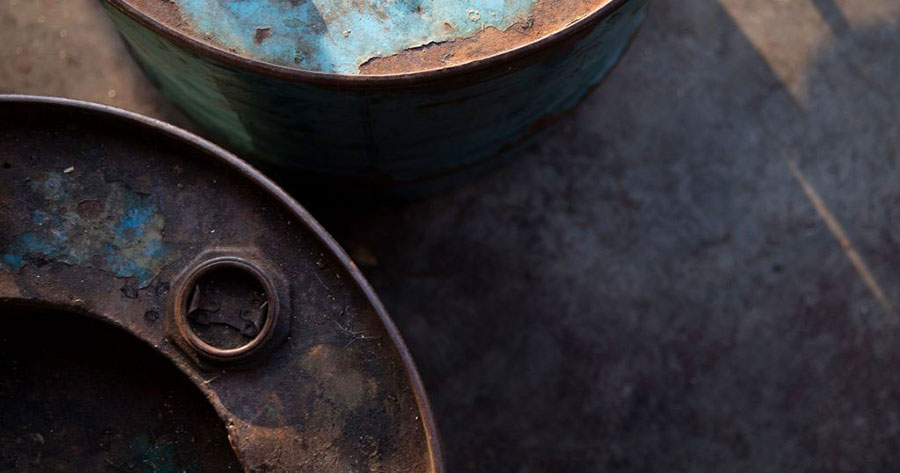 An abstract image looking at the top of two rusted blue metal barrels.