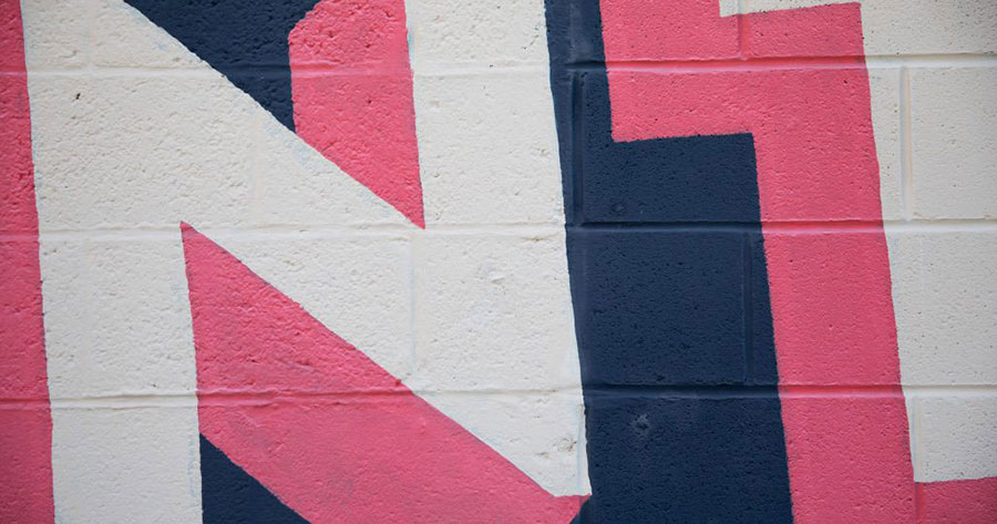 A close-up image of wall art from Downtown Johnson City. The art is pink and white lettering on a navy background.