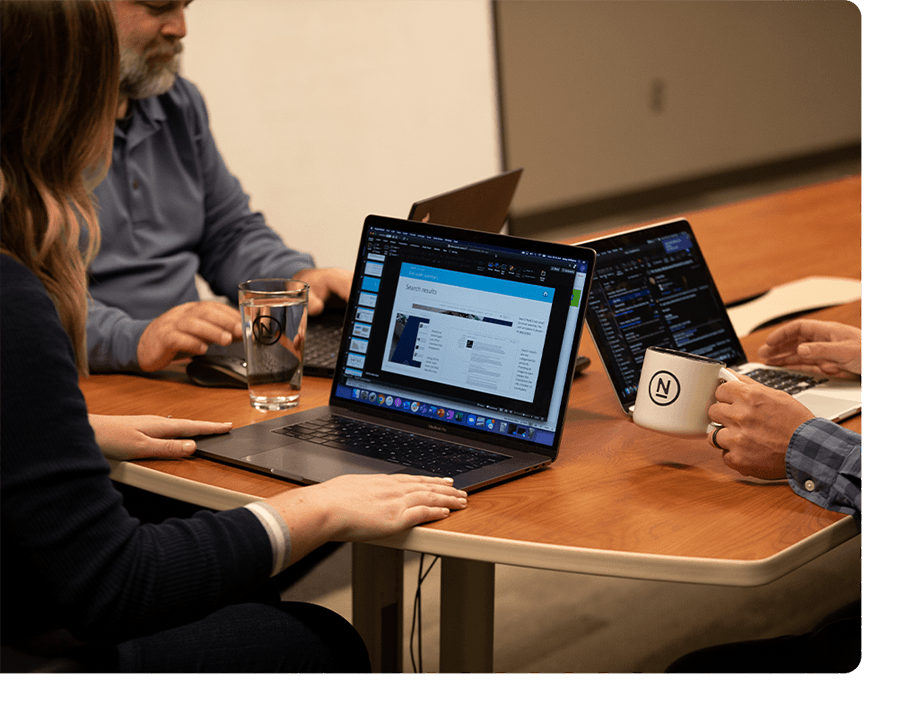 A Ntara team working on laptops together in a conference room.
