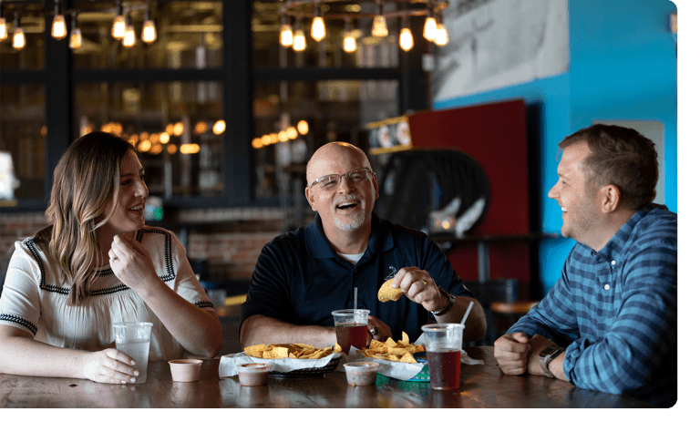 Three Ntara employees laugh together at a meal. Laughing and enjoying each other's company.