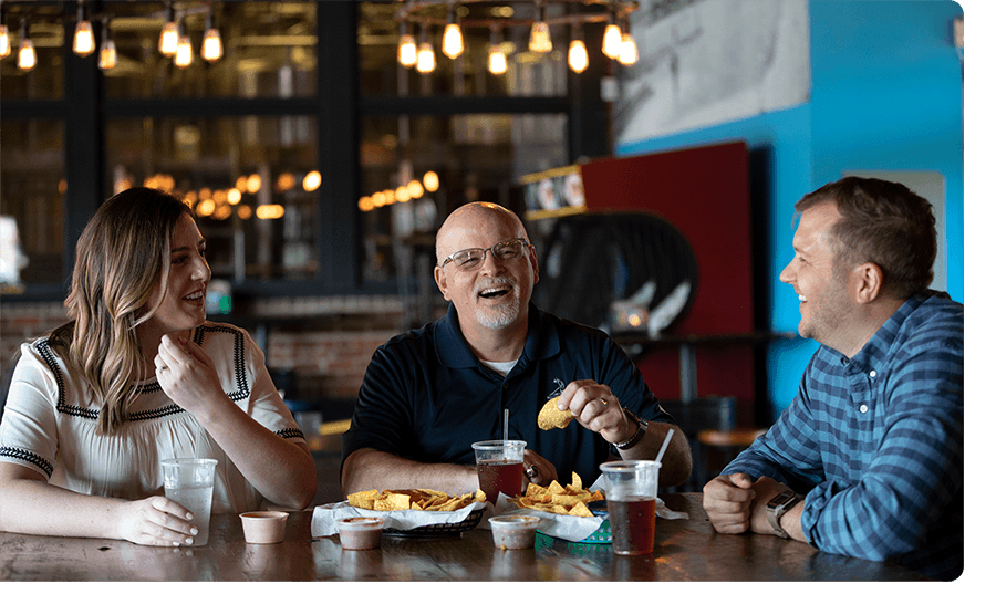 Three Ntara employees laugh together at a meal.
