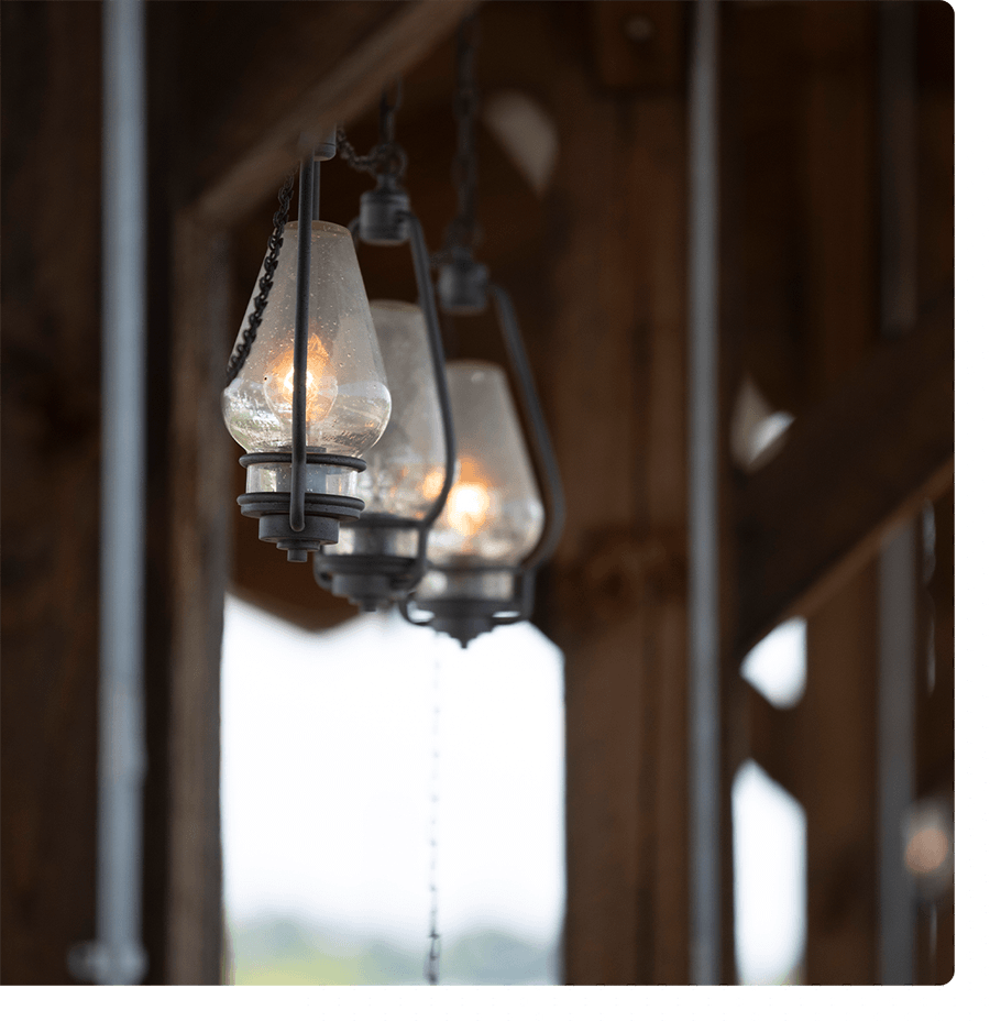 3 lanterns handing outside under a wood pavilion