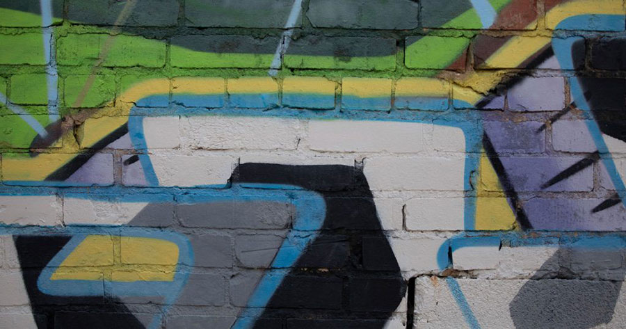 A close up view of some colorful graffiti on a brick wall in downtown Johnson City. The graffiti is gray, white, black, lime green, and yellow, with outlines of blue.
