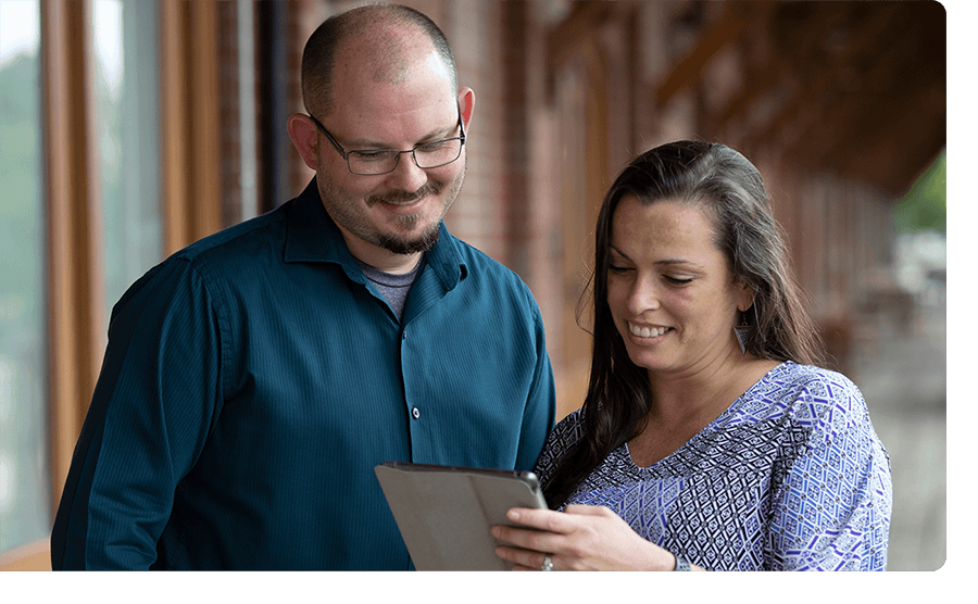 A woman showing a man something on an iPad.