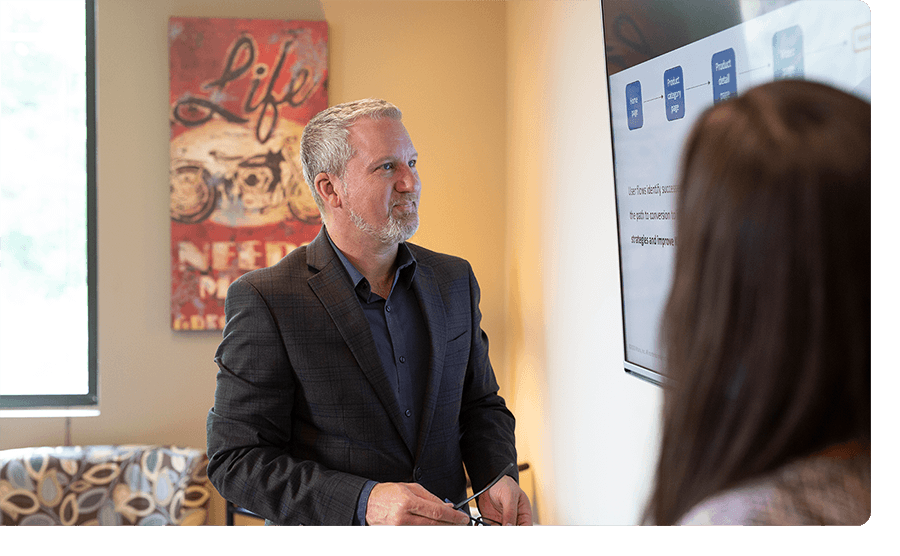 Man with gray hair and goatee reviewing a presentation with a female coworker.
