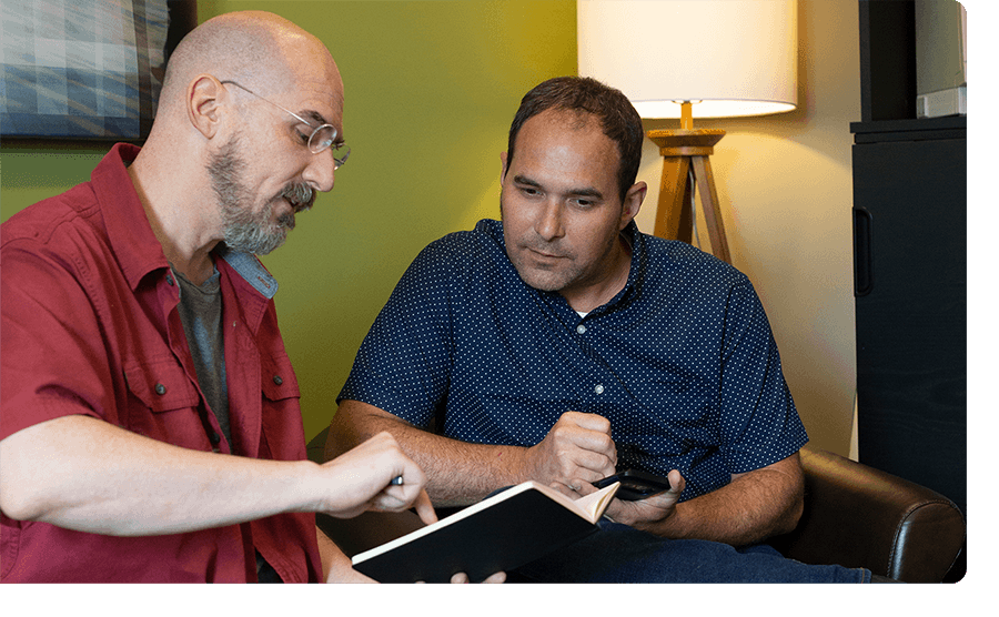 Two Ntara employees review some notes in a notebook.