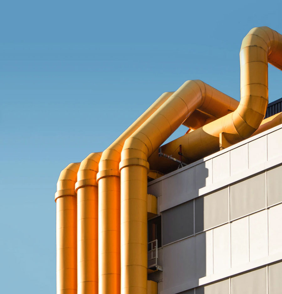 Yellow pipes scaling a building with a blue sky.