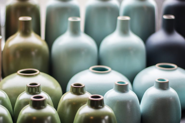 Green, light blue, and black ceramic pottery, neatly arranged by color.