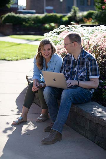 photo of two people outside with a laptop
