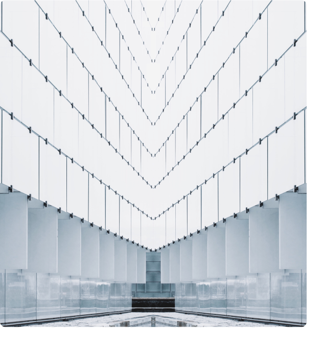 Abstract image of a very tall room with floor-to-ceiling windows. The lower level of the windows are gray and show nondescript reflections from inside the room. 