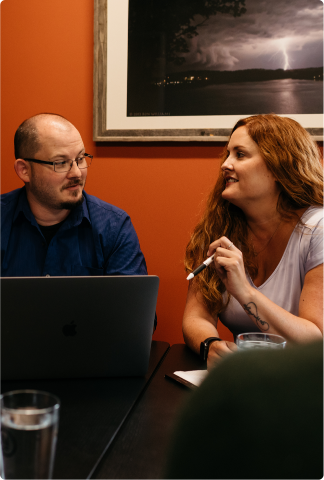 Man and woman sitting at a computer having a conversation