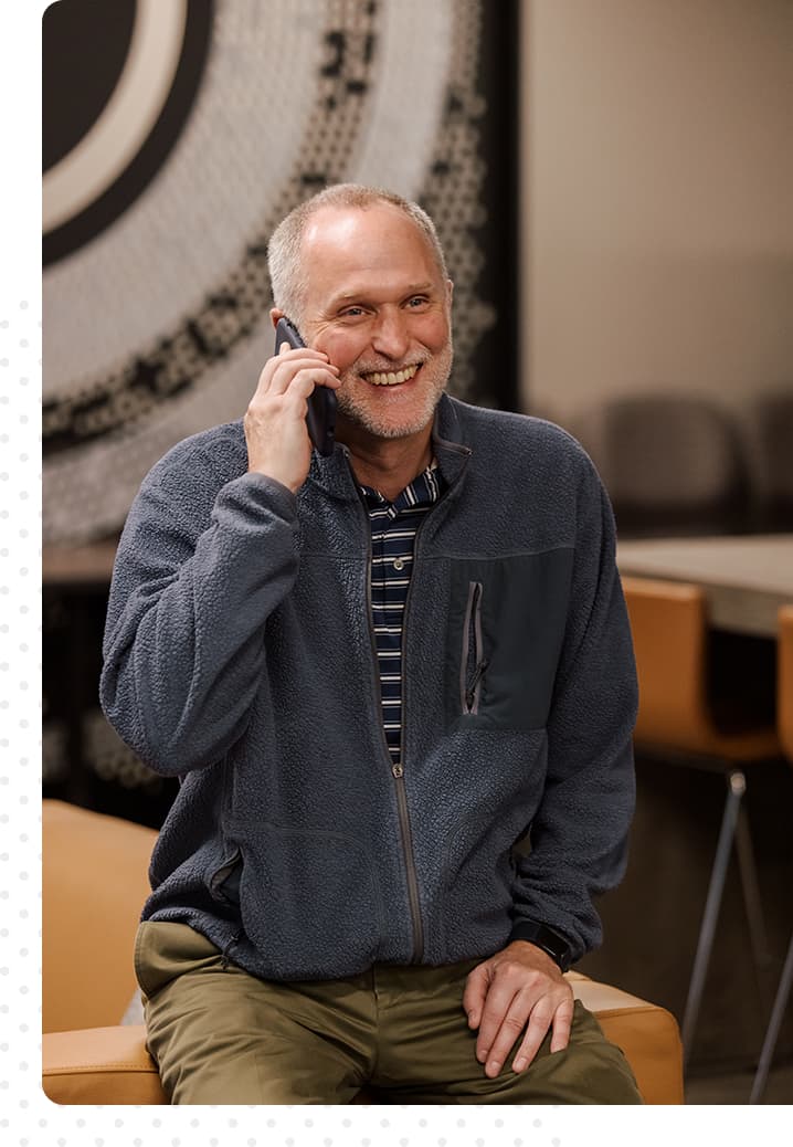 Image of man seated, talking on phone, smiling